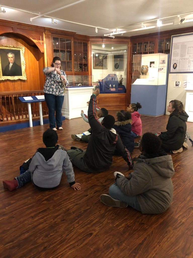 A James Monroe museum employee talking to a group of students in the museum.